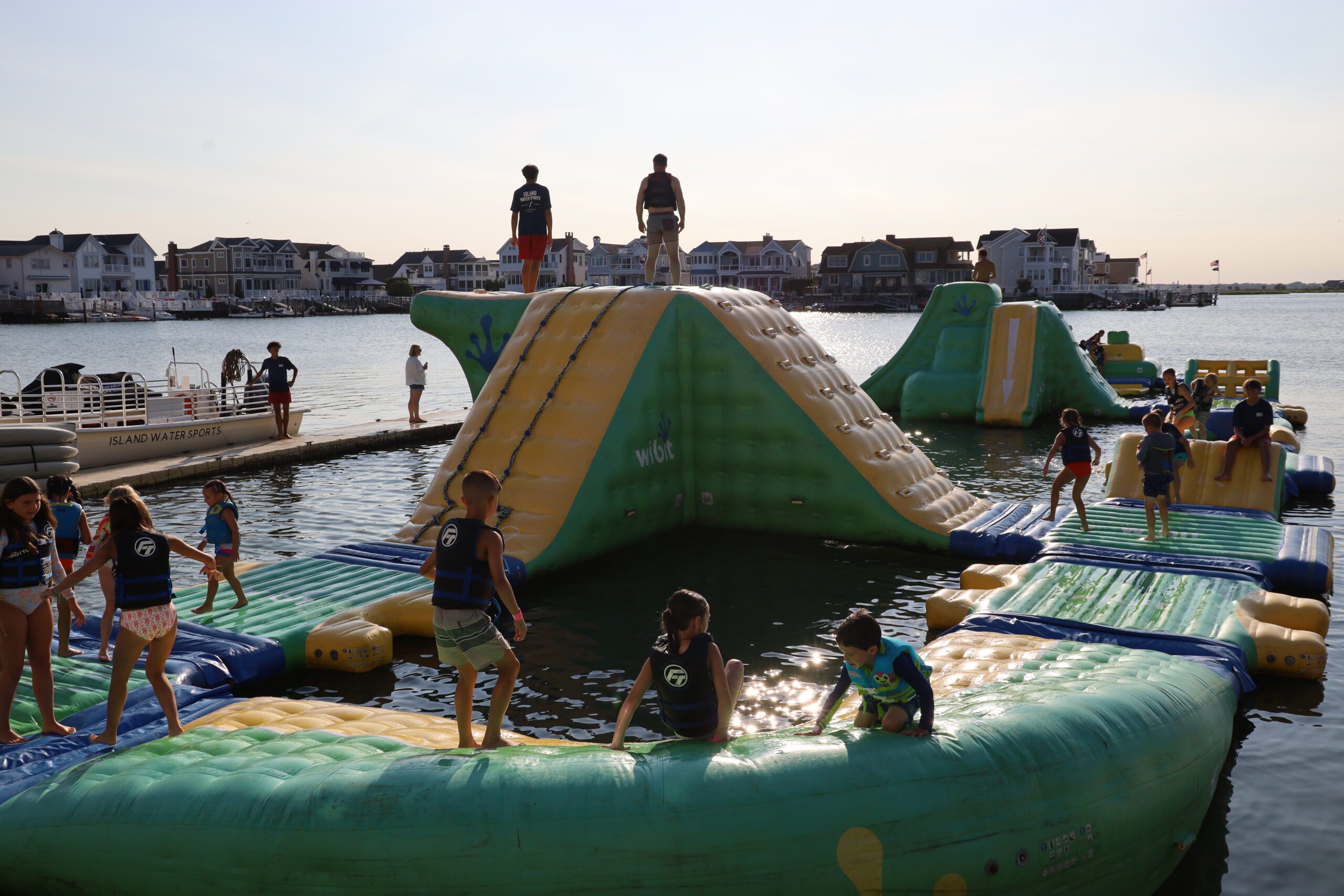 Kids having fun on the full Stone Harbor aqua park course during a private event with a lifeguard on duty