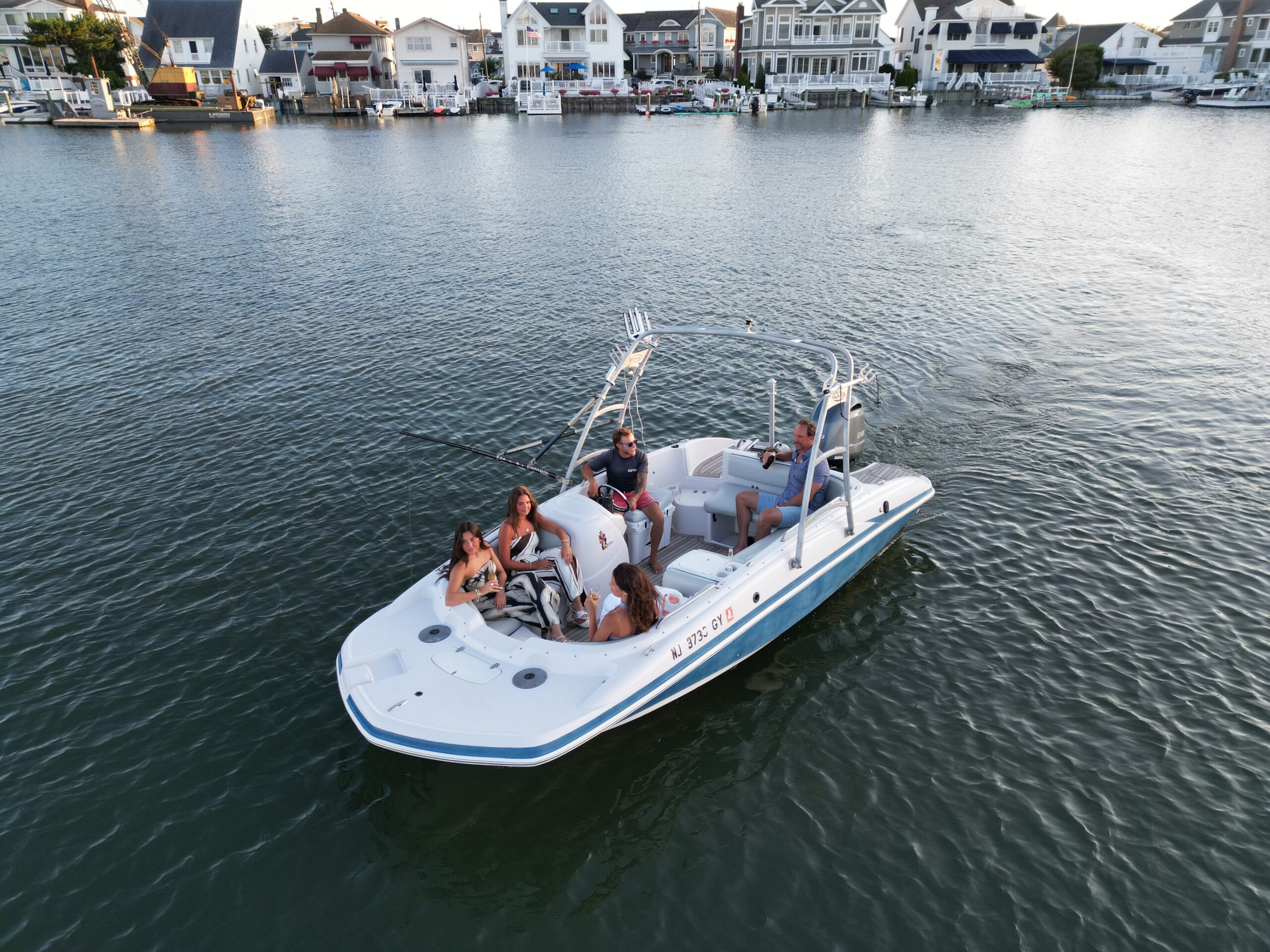The Basin Cruiser cruising past Avalon and Stone Harbor bayfront mansions at golden hour during a private back bay charter