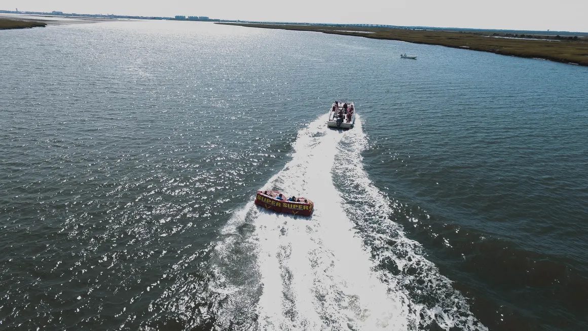 Aerial view of Island Water Sports boat pulling a tube through the Stone Harbor back bay
