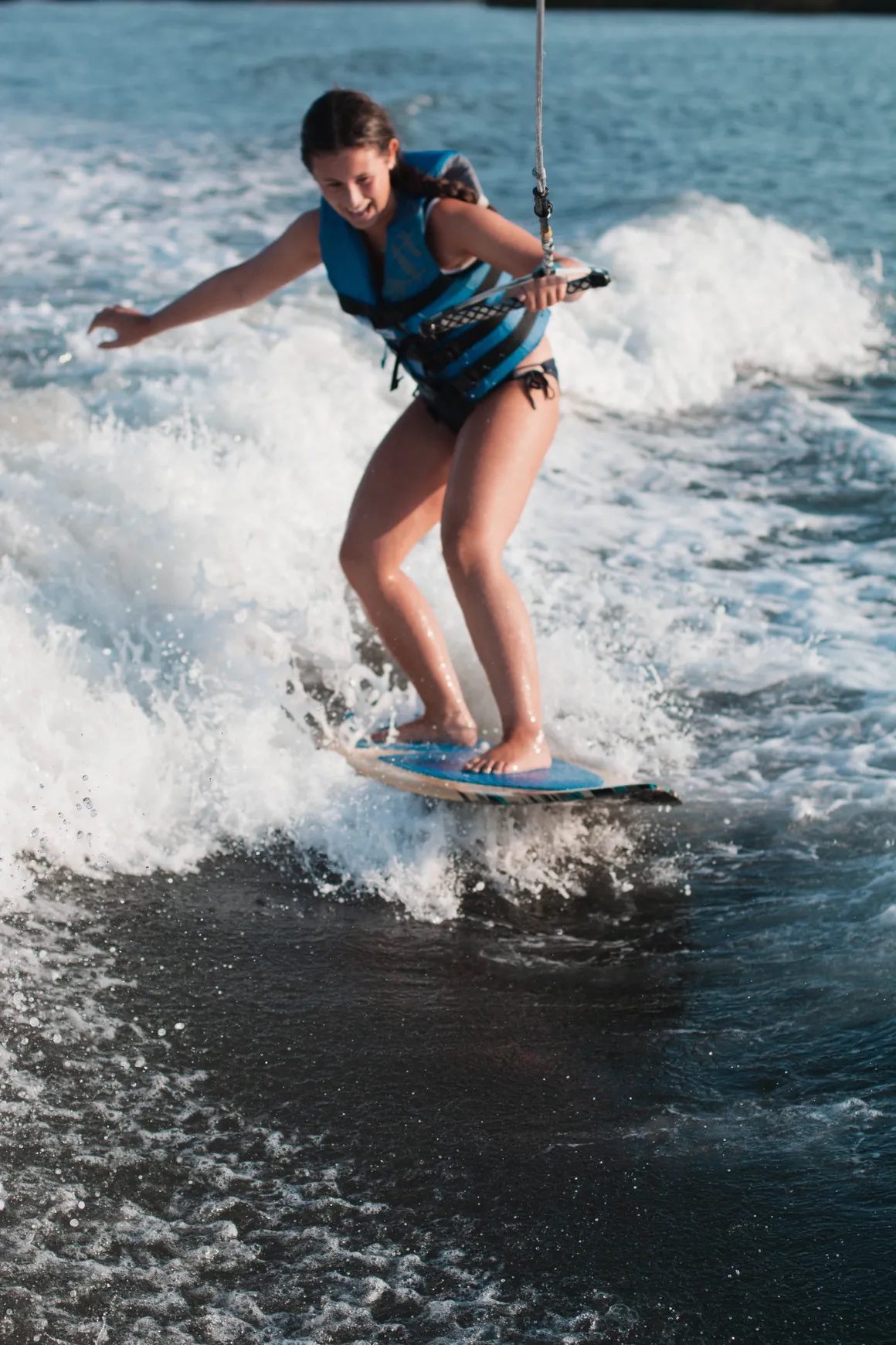 Young woman wakesurfing through golden hour spray on a Stone Harbor back bay session with Island Water Sports.