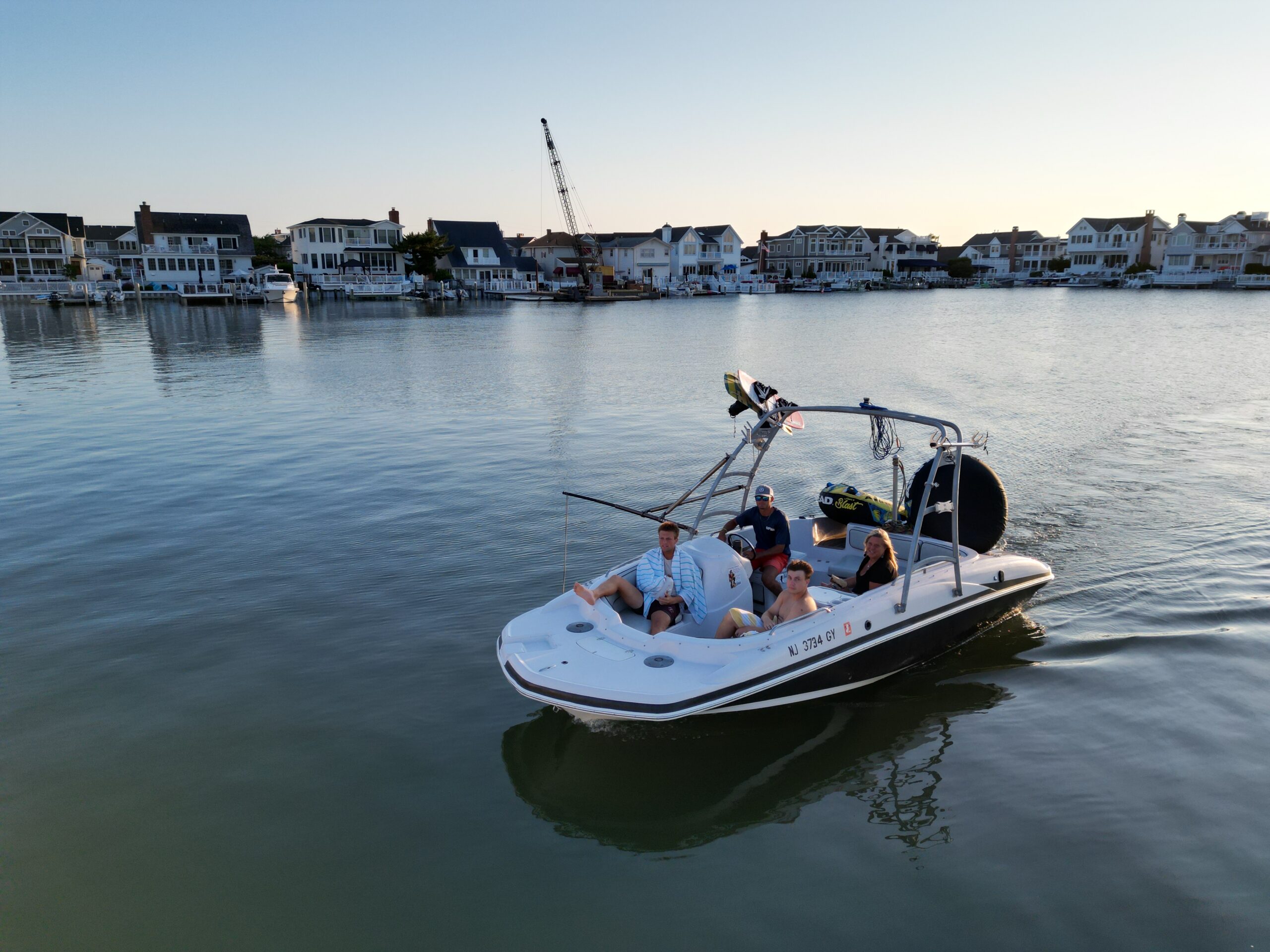 Island Water Sports ski boat cruising the Stone Harbor back bay at golden hour, bayfront homes lining the shore.