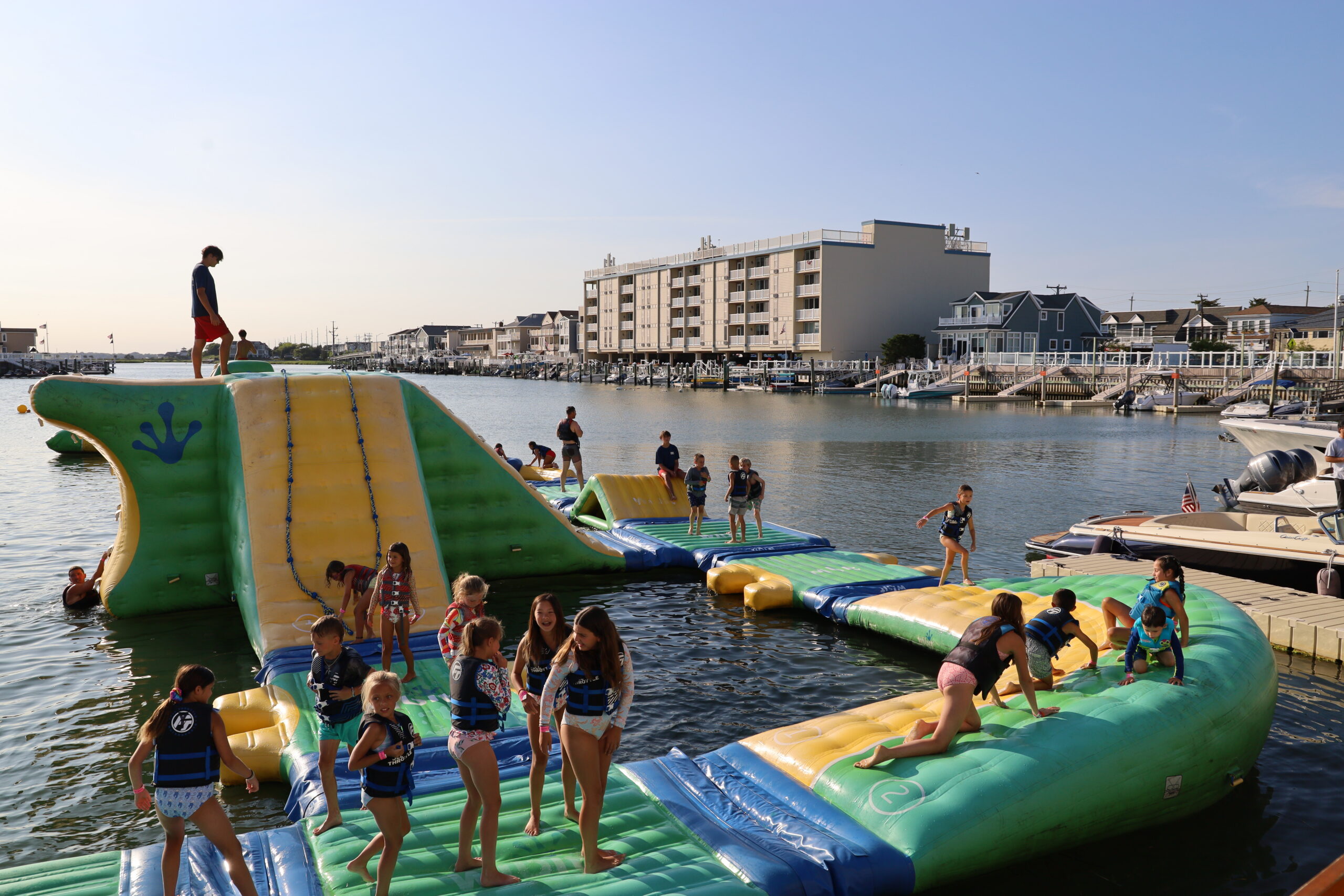 Kids playing on the Island Water Sports inflatable Aqua Park in Stone Harbor at golden hour.