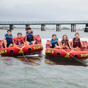 Two groups of kids riding tubes behind an Island Water Sports boat in Stone Harbor