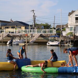 Group of kids playing on the floating water park at Island Water Sports in Stone Harbor