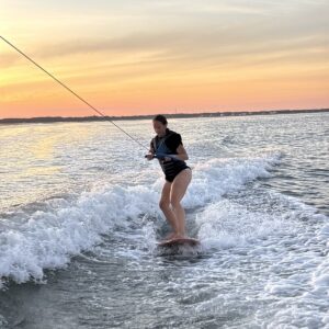 Wakesurfer riding the wake at sunset behind an Island Water Sports boat in Stone Harbor
